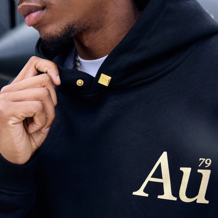 Close-up of person wearing a black hoodie with 'Au' logo and gold accents