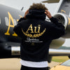 Person wearing a black hoodie with gold 'Au' logo on the back.