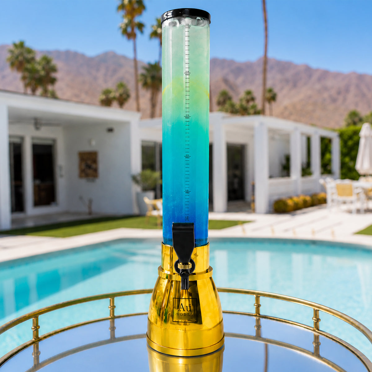 Au Vodka branded drink tower filled with blue and yellow cocktail on a poolside table