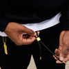 Person adjusting a black lanyard with a gold clasp
