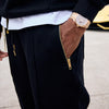 Person wearing black joggers with gold zip pockets