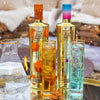 Two bottles of Au Vodka with orange and blue caps, surrounded by glasses filled with a clear liquid.
