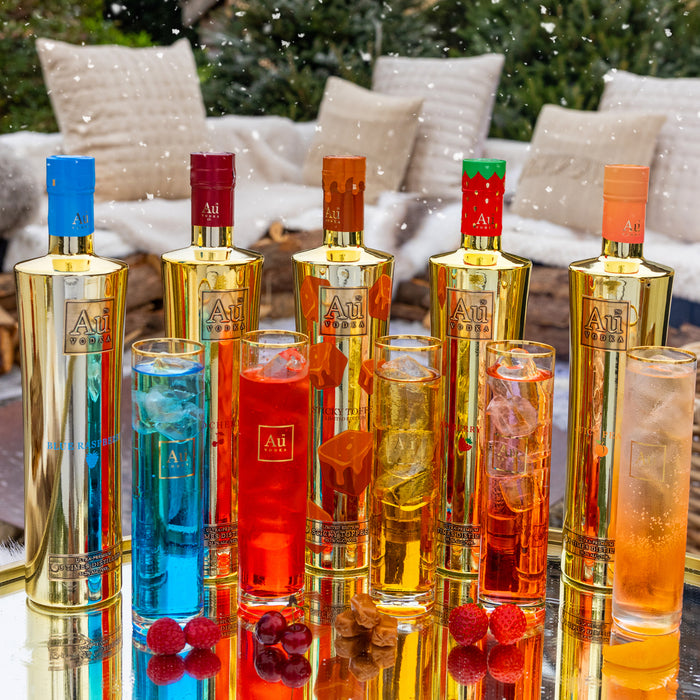Colorful bottles and glasses with 'Au' branding on a reflective surface.