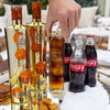 Two bottles of Au cocktails with a glass of cocktail and Coca-Cola bottles on a snowy surface.