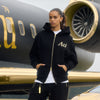 Person wearing a black hoodie with 'Au' logo in front of a luxury airplane