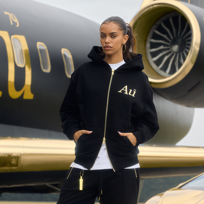 Person wearing a black hoodie with 'Au' logo in front of a luxury airplane