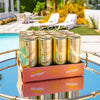 Case of Au Vodka Juicy Peach drinks on a table by a poolside.